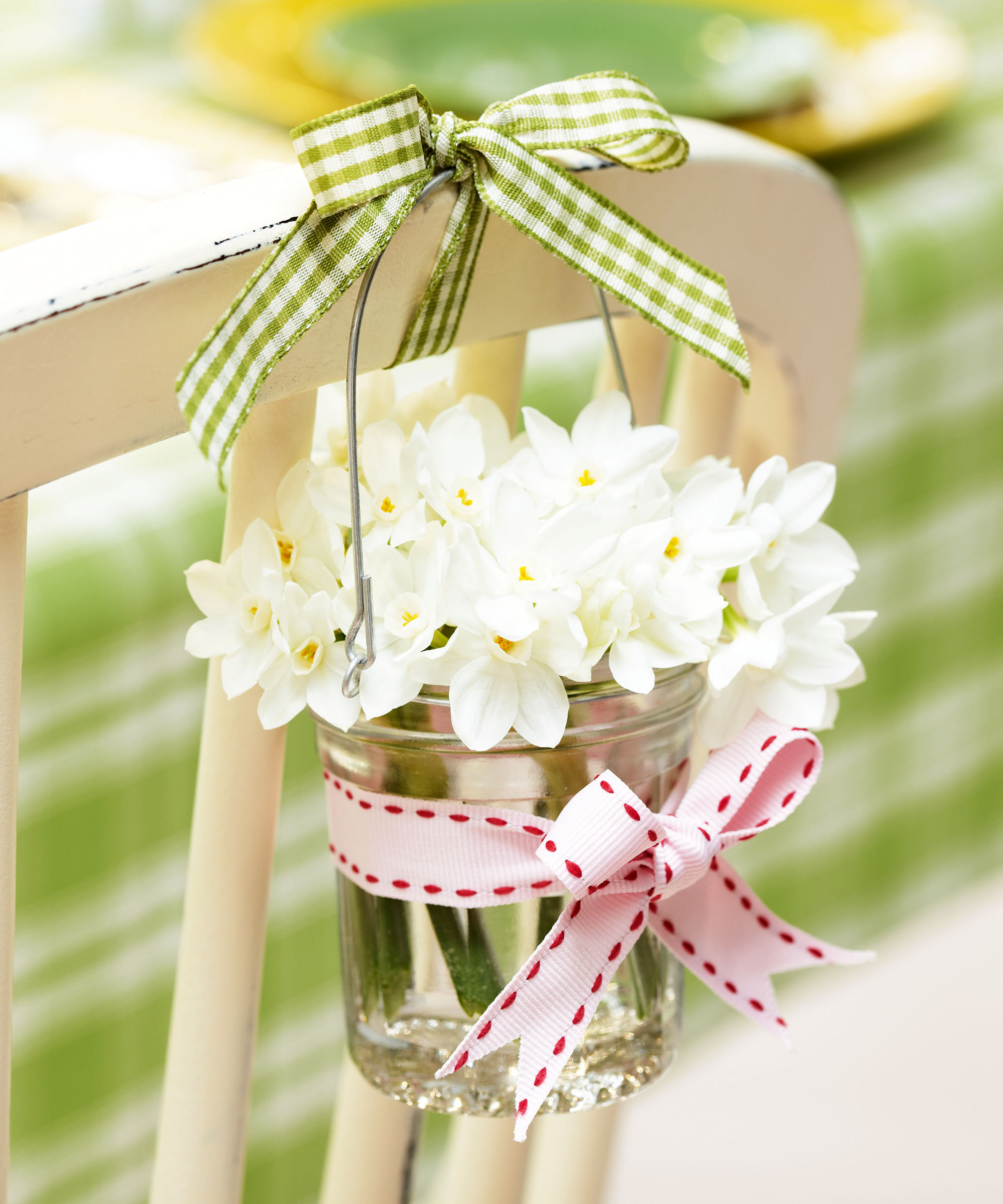 Jar filled with white daffodils hanging on chair back