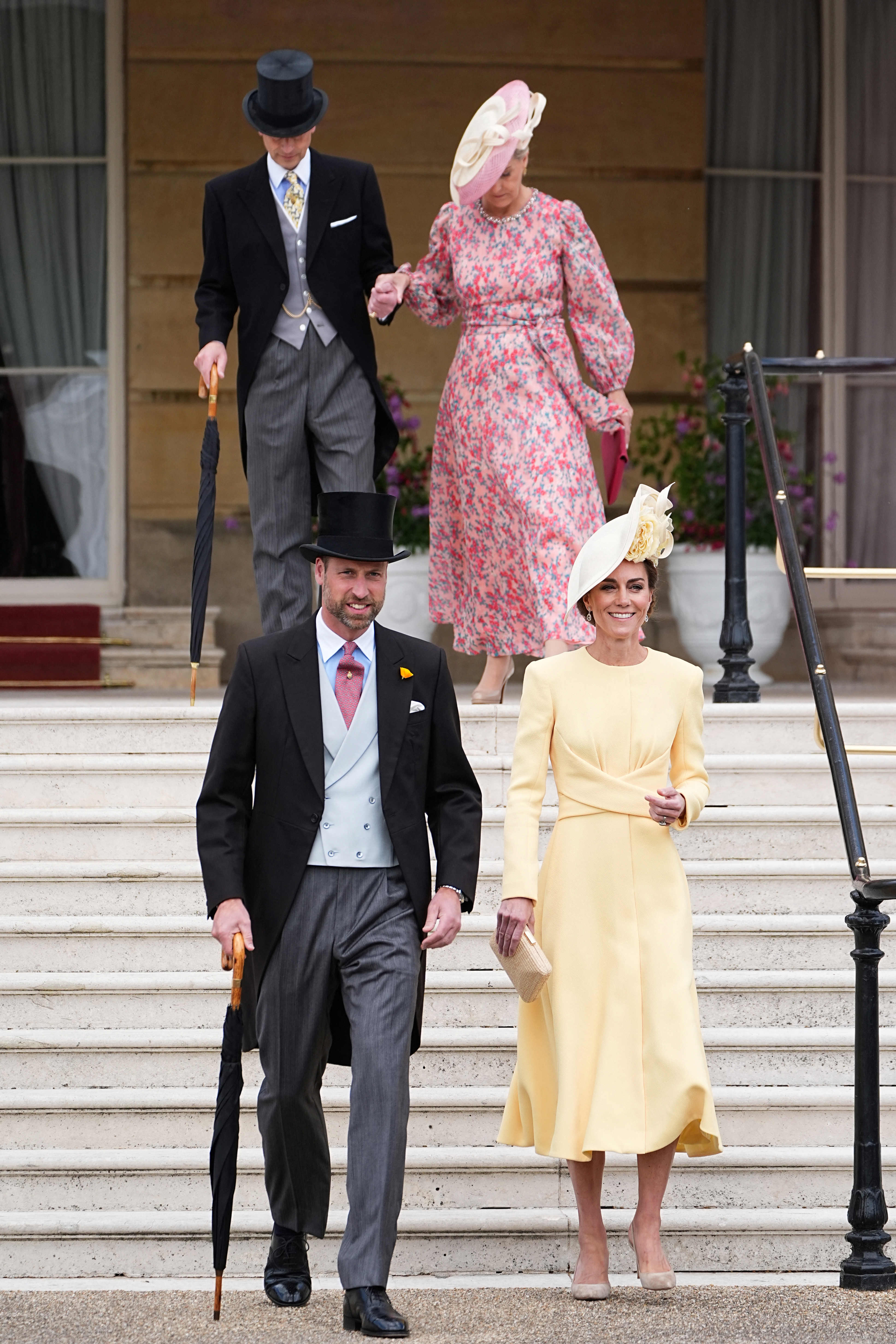 Prince William and Princess Kate walking down the stairs at a palace garden party with Duchess Sophie and Prince Edward behind them