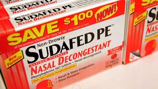 a box labeled "sudafed PE, nasal decongestant" on a pharmacy shelf