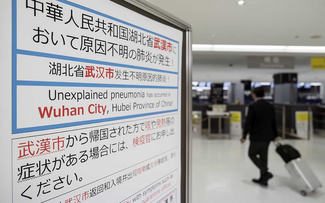 NARITA, JAPAN - JANUARY 17: A passenger walks past a notice forpassengers from Wuhan, China displayed near a quarantine station at Narita airport on January 17, 2020 in Narita, Japan. Japan&amp;#039;s