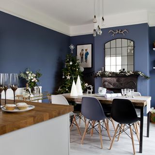Blue dining room with table and chairs, fireplace and Christmas decorations