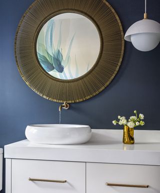 Navy bathroom with white vanity unit and basin, large round mirror, white pendant globe light