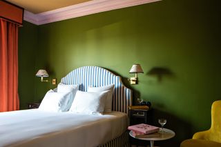 A bright green hotel bedroom with striped bedhead