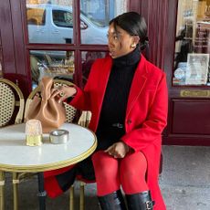 a woman sitting outside a cafe with her hair in a low bun