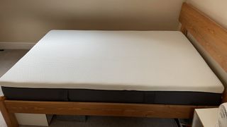 Image shows the Emma Mattress placed on a wooden bed frame during testing