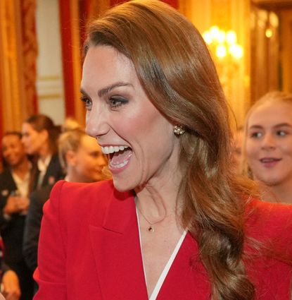 Princess Kate wearing a red blazer, laughing and pointing 
