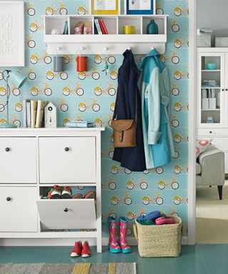 Blue-bicycle wallpaper with a white storage cabinet and a wall-mounted clothing race with clothing accessories