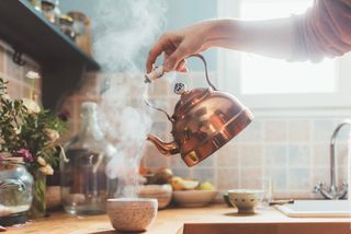 Copper kettle pouring a hot drink in a kitchen at home