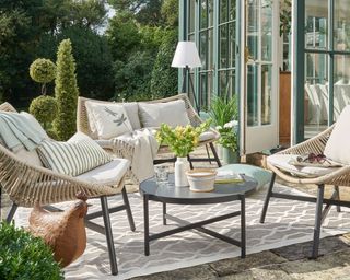 outdoor living area with string chairs, grey patterned outdoor rug and black coffee table