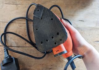 An orange hand sanding tool