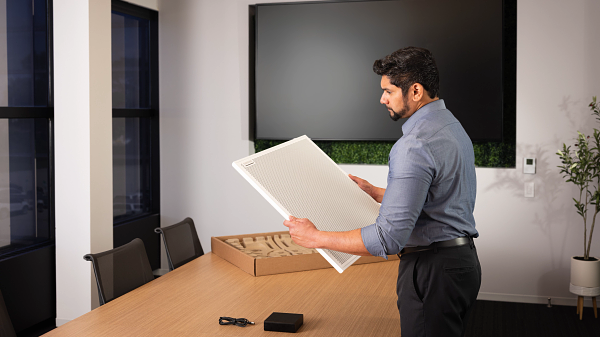 The new Shure Audio Conferencing Kit being taken out of the box by a male employee in a conference room. 