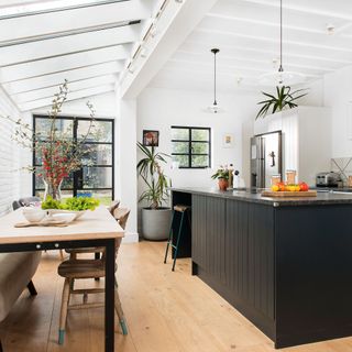 kitchen with black island, dining table and high ceilings