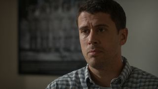 Still from the T.V. show For All Mankind (season 4, episode 1). Close up of a man with short dark hair wearing a blue and white plaid shirt. He looks worried.