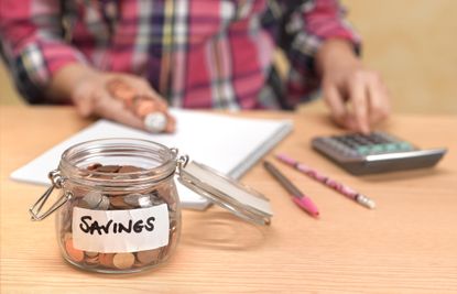 Person counting pennies in a jar using calculator