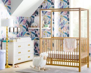 Girls nursery with printed wallpaper, canopy crib, white and gold chest of drawers and white and gold lamp by Wayfair