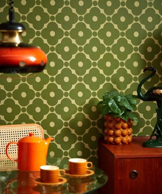 A dining room with bright green floral wallpaper and a glass table