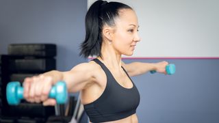 A woman performing a dumbbell lateral raise