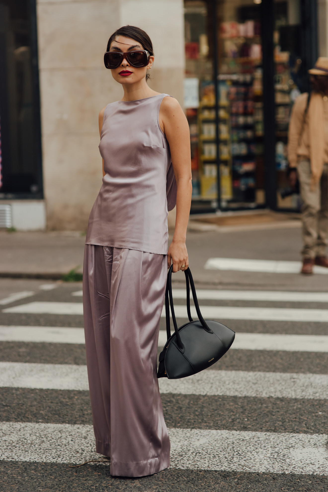 Woman in a pale violet satin set and a Nina Ricci Le Bal shoulder bag.