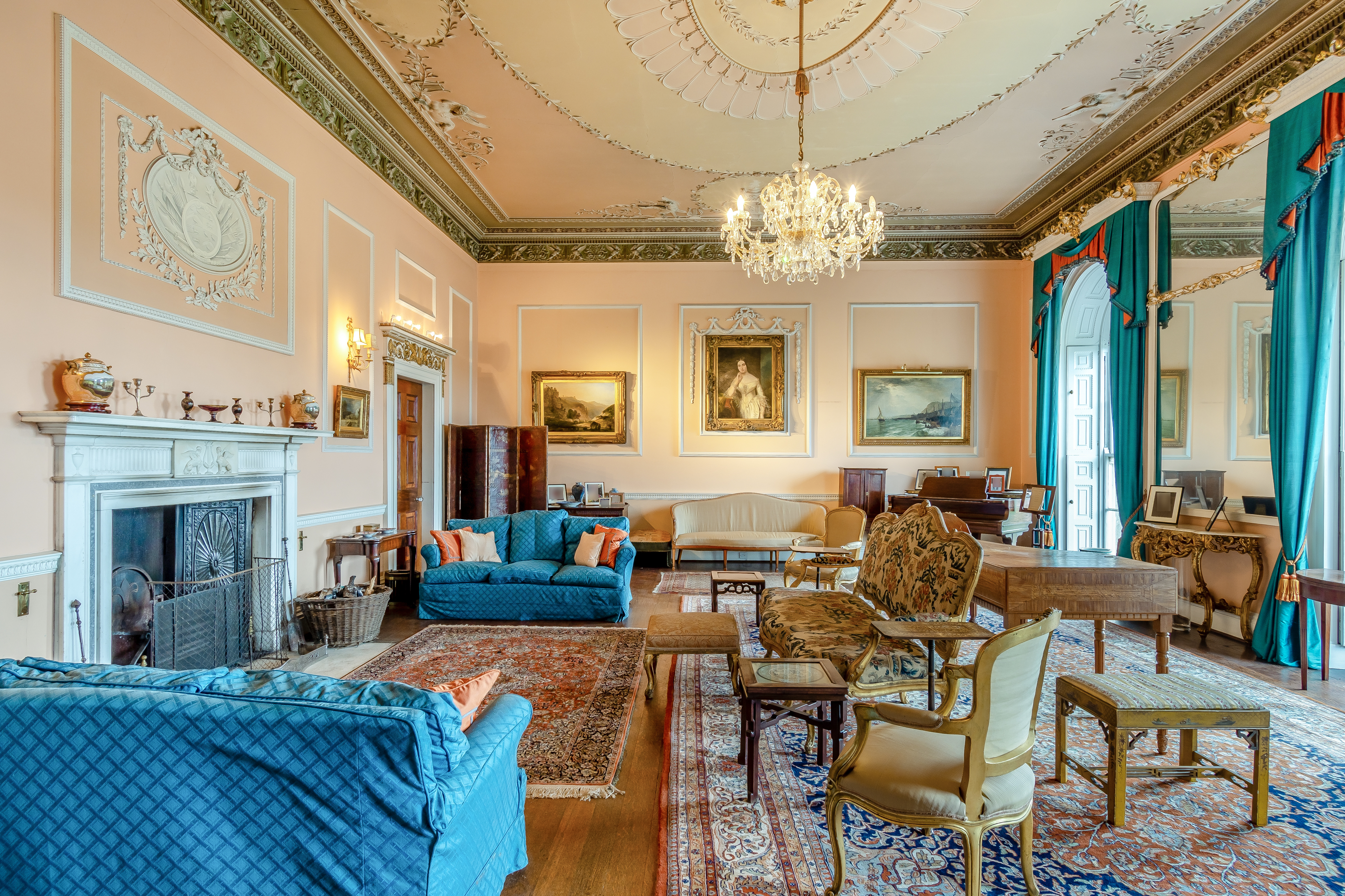 Teal sofas and gilded chairs in a room with a chandelier