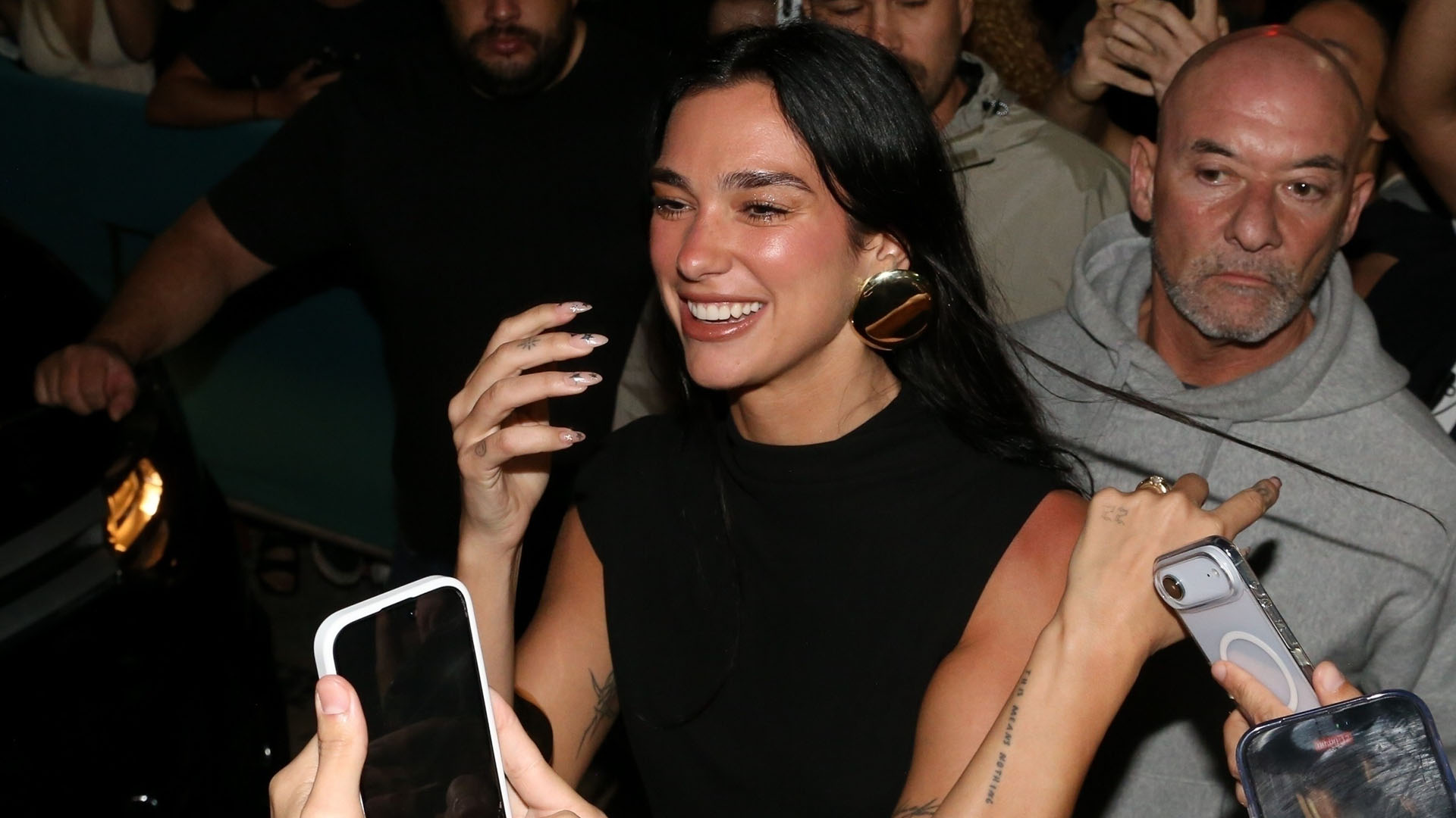 Dua Lipa wearing a black top, zebra bag, dark wash jeans