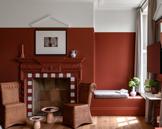 A fiery red wall and fireplace surround with wicker chairs and pair of low round wooden coffee tables