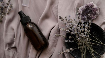 Amber glass bottle on a purple towel with dried flowers