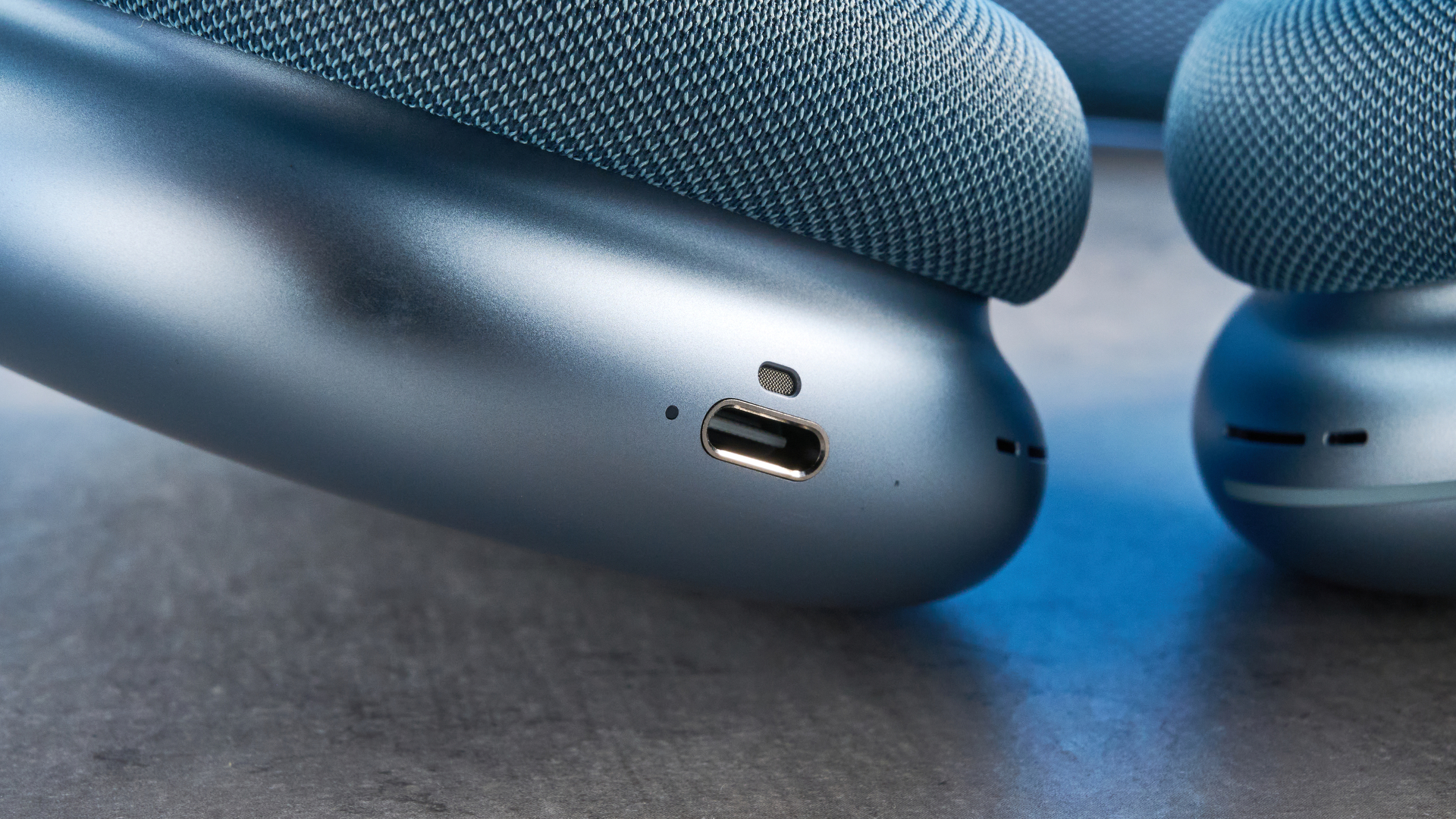the apple airpods max 2 in blue photographed against a blue tom's guide background, showing the mesh headband, anodized aluminum ear cups, carry case, and controls