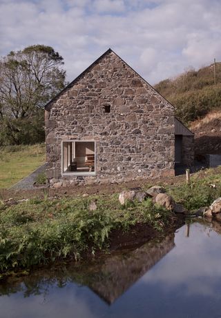 stone wall and pitched roof shape of community dining hall, Croft 3 by London based studio fardaa