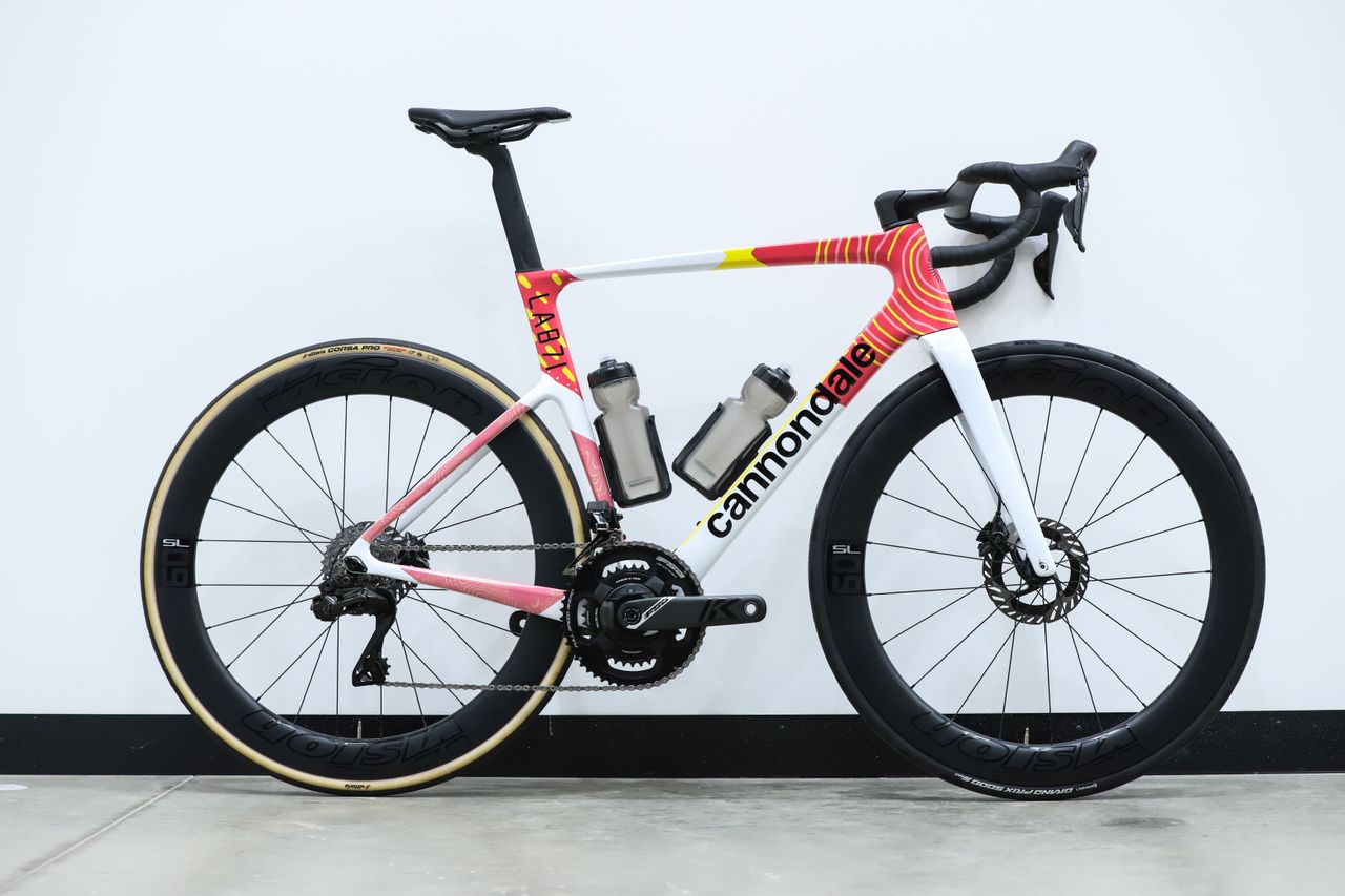 A team-edition Cannondale SuperSix Evo 4 stands against a white wall