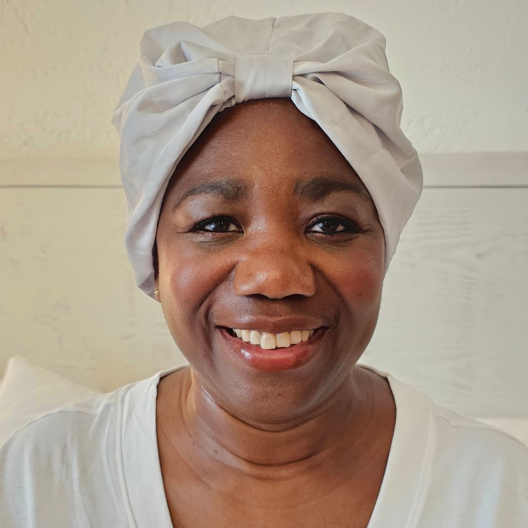 Joyce Connor pictured wearing the x silk hair wrap, tied around her hair and smiling to the camera