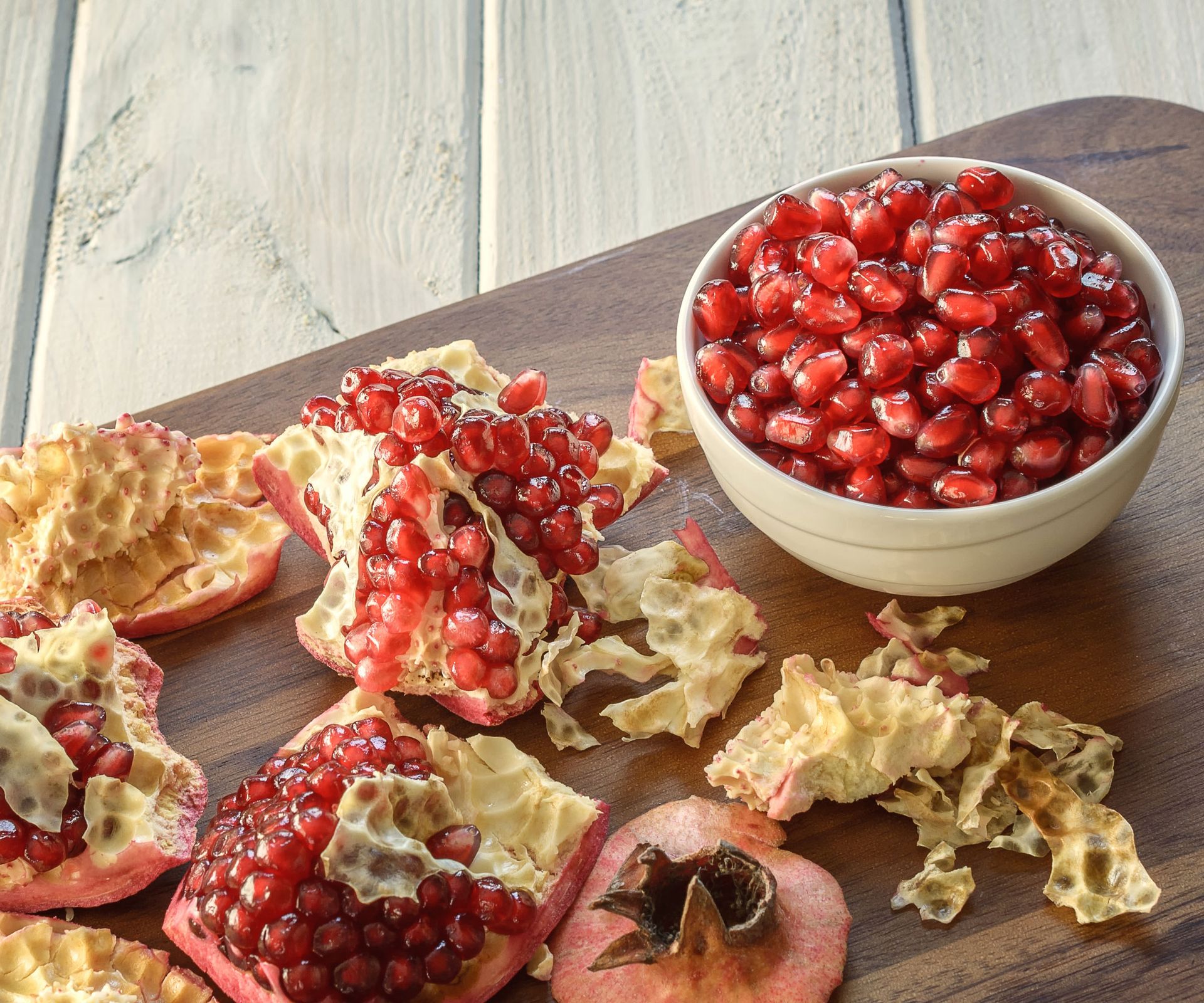 pomegranate fruit in dish next to fruit scraps on chopping board