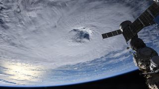 a hurricane seen from space, with a space station vehicle hanging in frame.