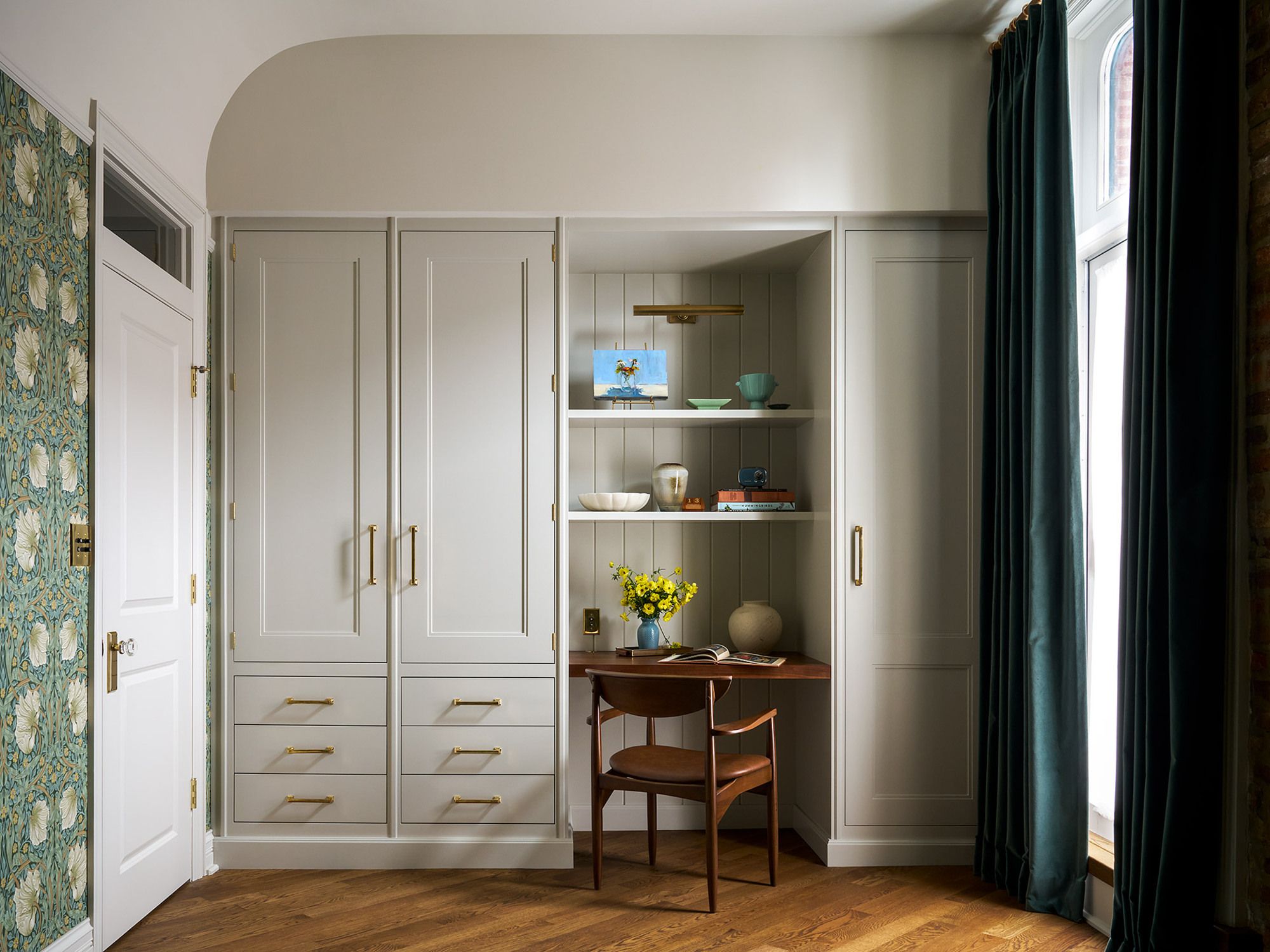 pale cream coloured wardrobes with a wooden floor and green patterned wallpaper 