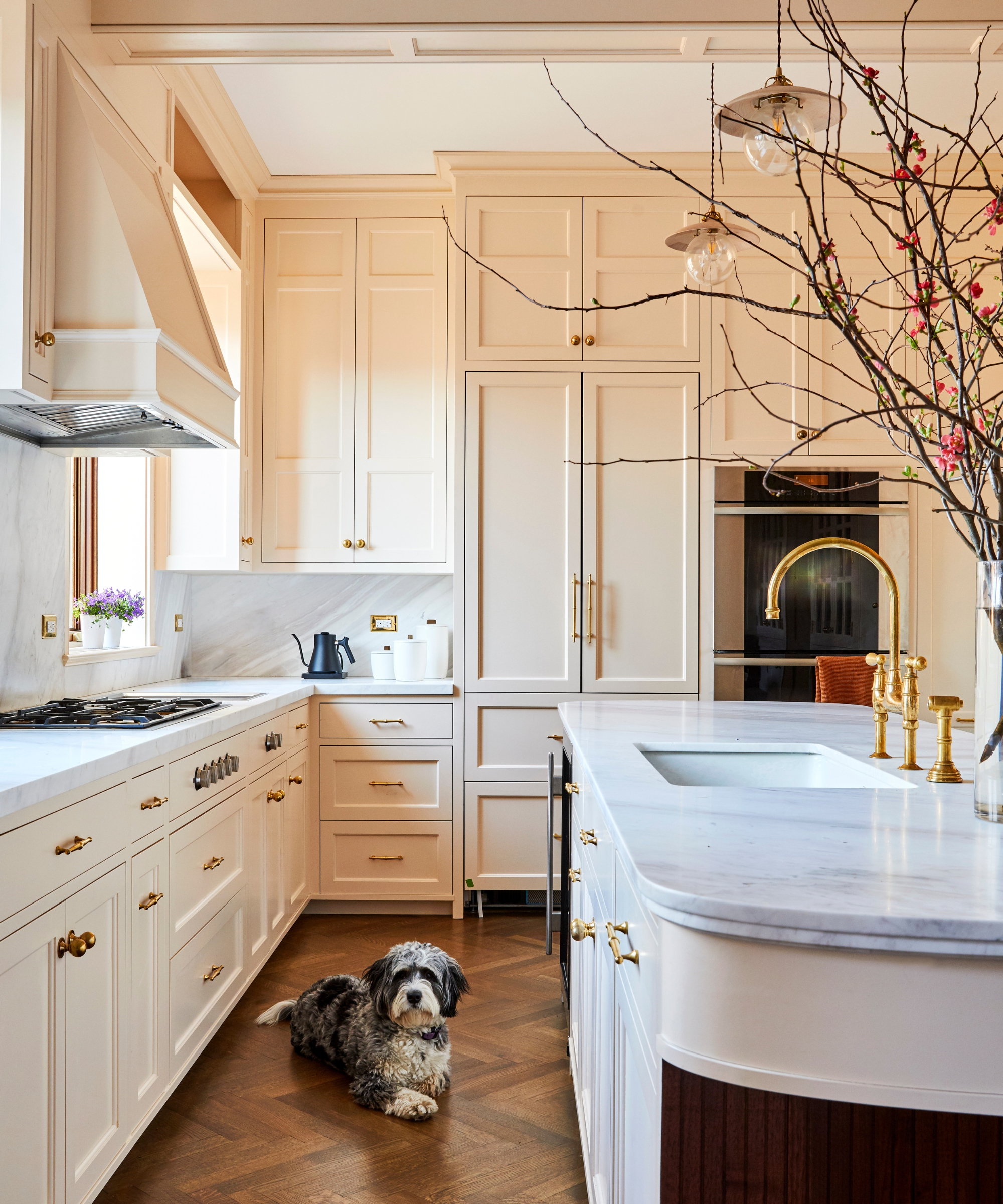 A small kitchen with soft pink cabinets and a curved island