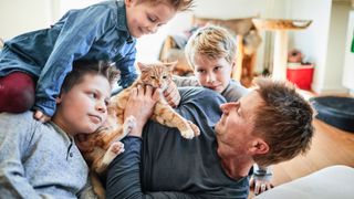 Man lying on floor with his three boys and their cat