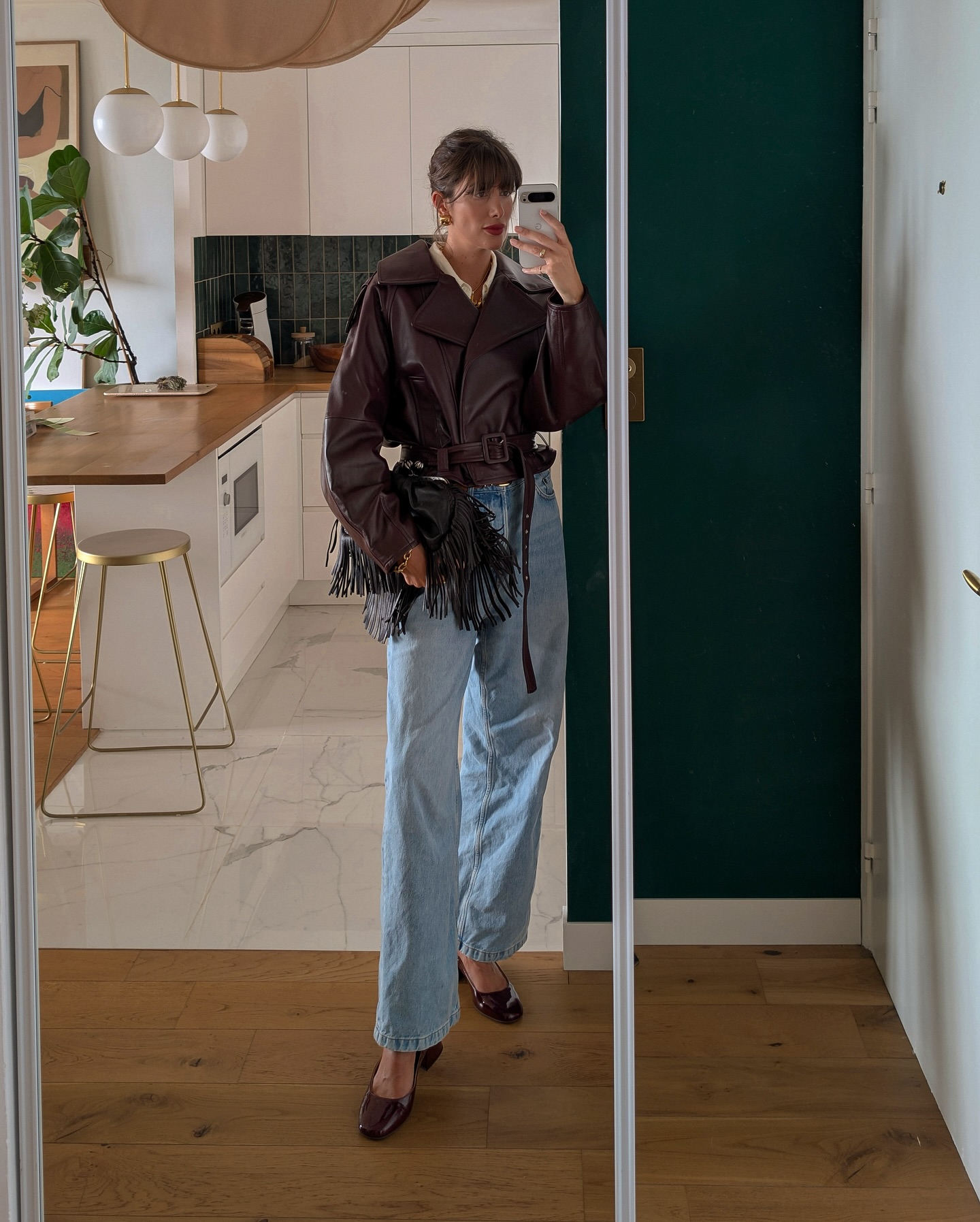 Julie wears a brown leather jacket, blue jeans and brown shoes