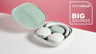 White Sonos Ace headphones in their case, on a table. "Big Savings" text in white is in the top right corner.