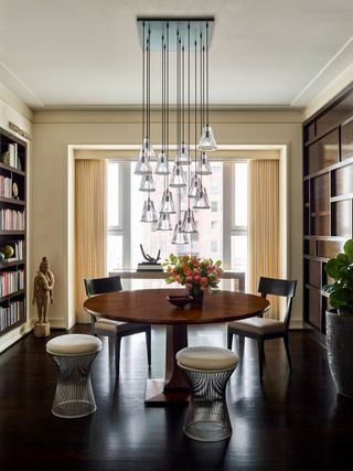 Round dining table with multi pendant chandelier above andwindow behind