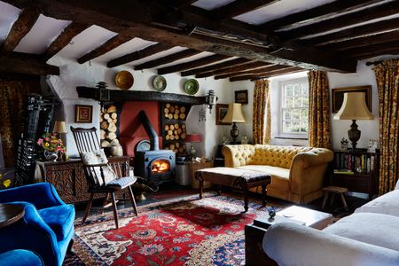 beamed ceiling with cottage and a stove and sofa