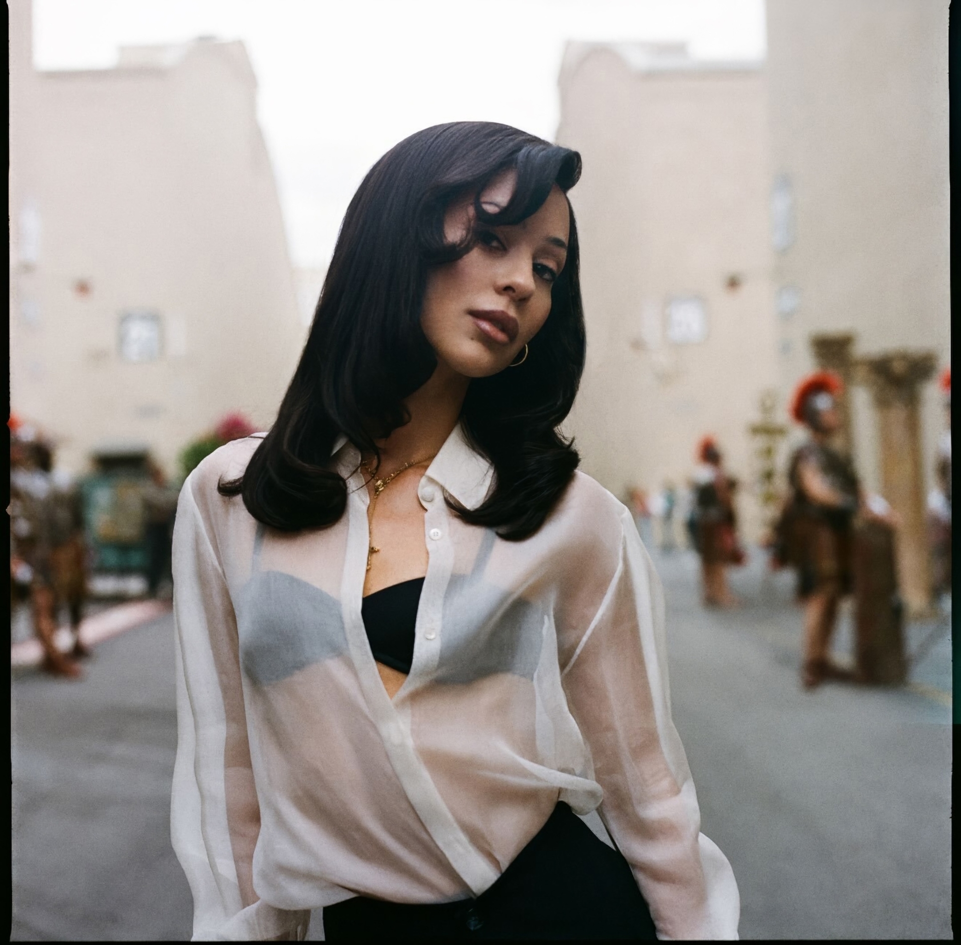 alexa demie as maddie wearing a sheer white shirt over a black bra on the set of a hollywood lot in euphoria season 3