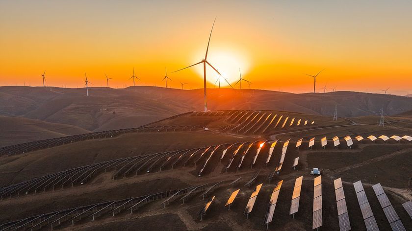 solar panels and wind turbines on rolling hills at sunset