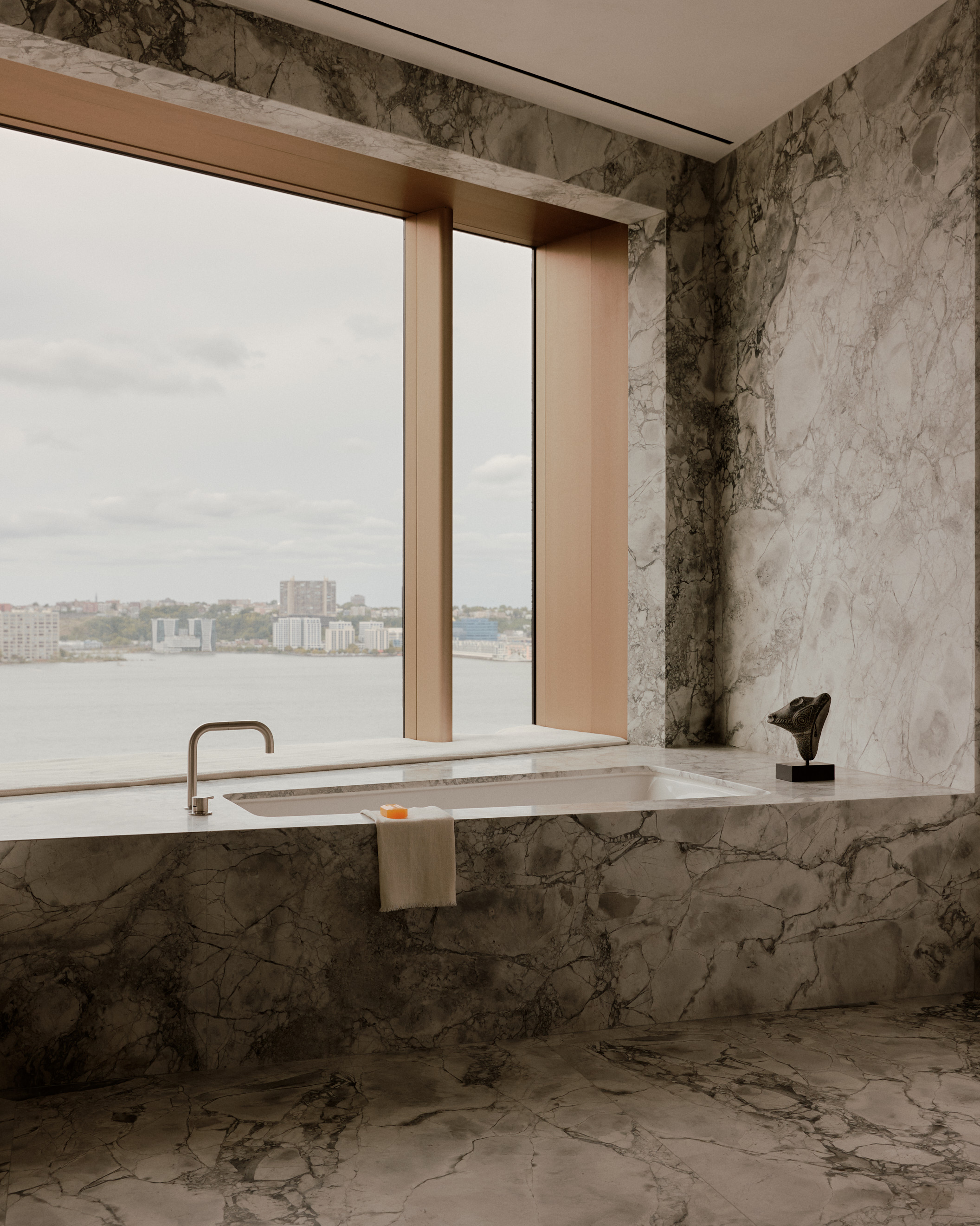 modern bathroom with angled built-in-bath and large window overlooking NYC