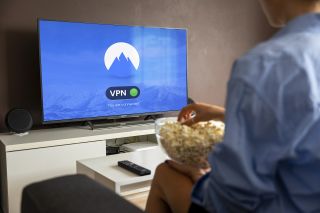 Jemand sitzt vor einem TV mit Popcorn und streamt via VPN