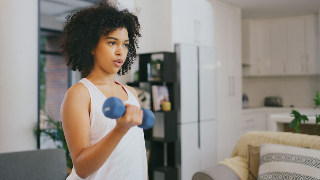 Woman doing a dumbbell curl in her living room