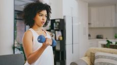 Woman doing a dumbbell curl in her living room