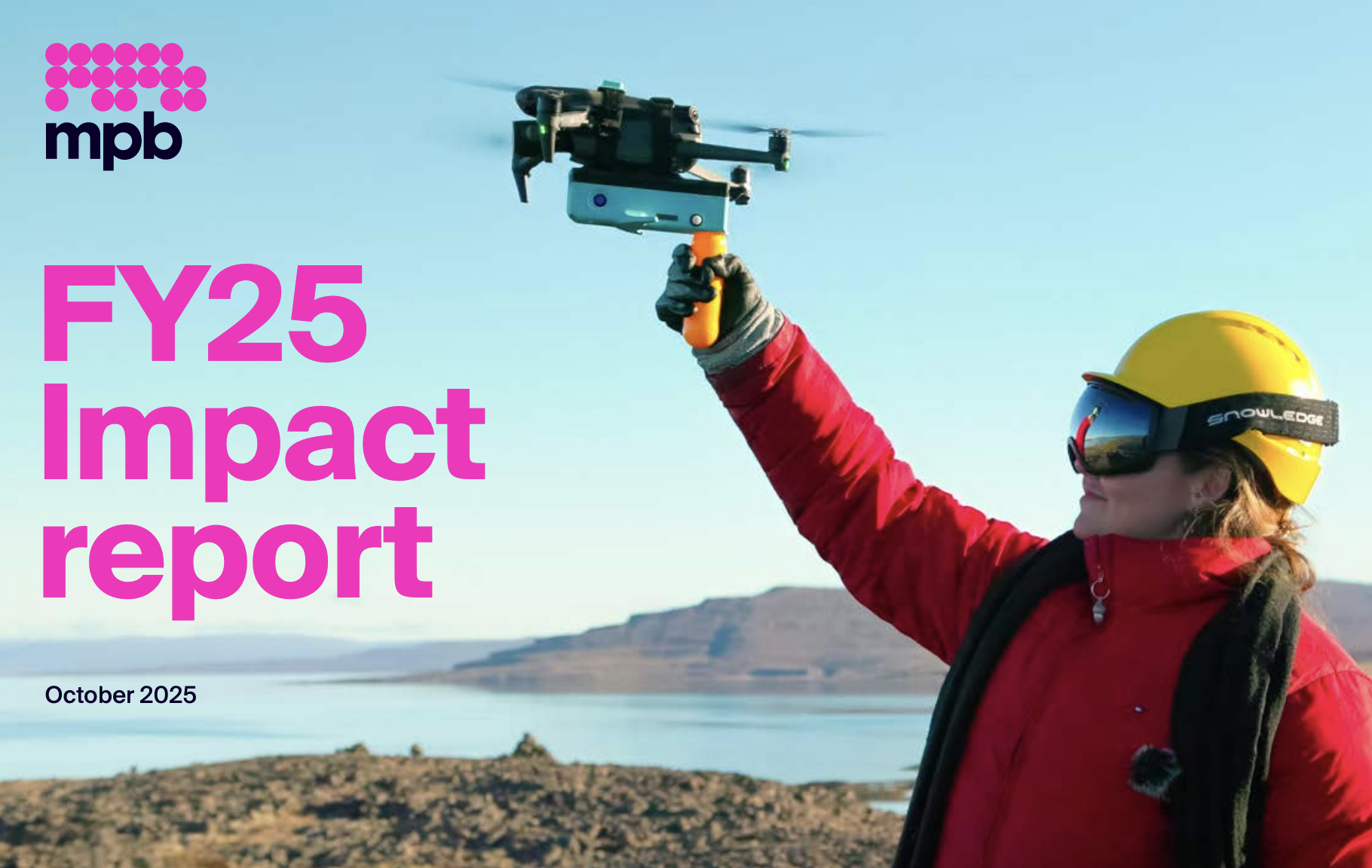 A person wearing a red jacket and yellow hard hat holds up a flying drone against a bright blue sky and a landscape with water and distant hills, with the text "mpb," "FY25 Impact report," and "October 2025."