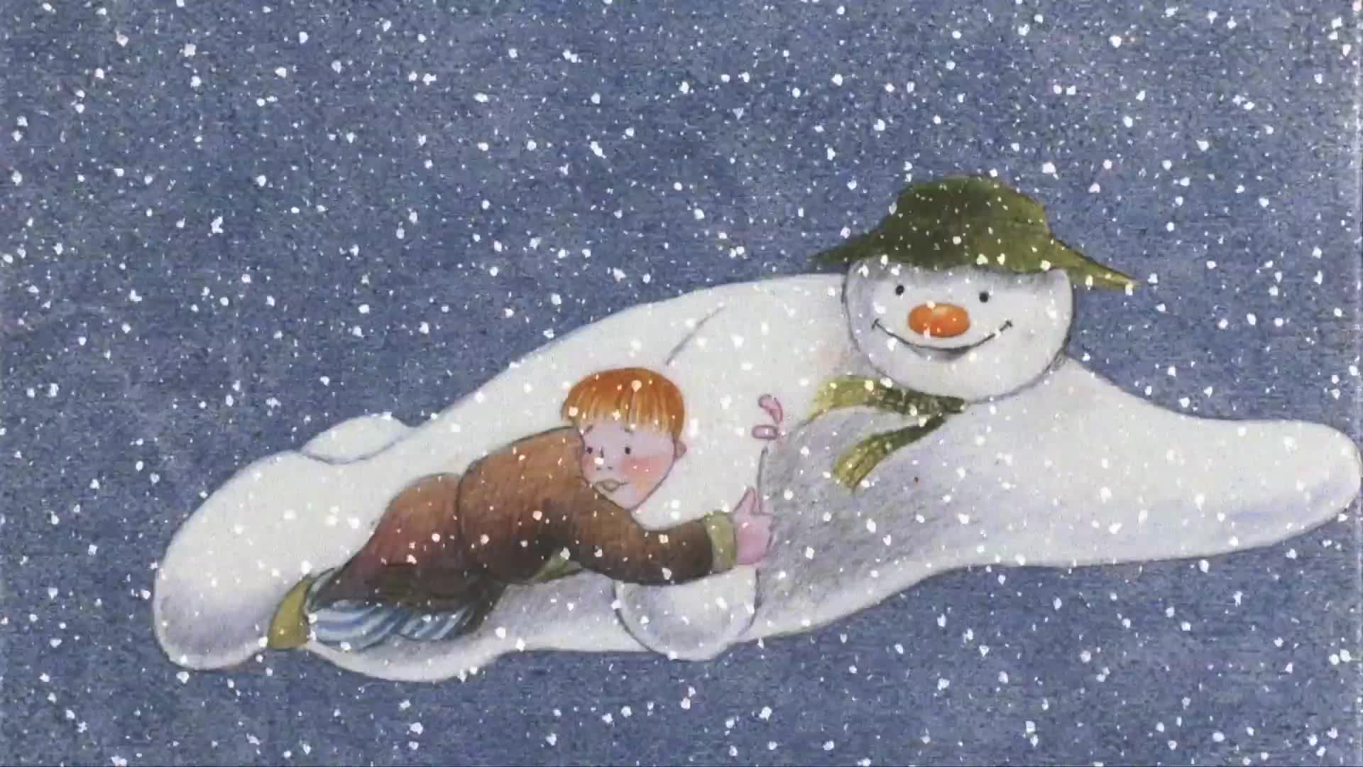A young boy in pajamas and a dressing gown clings to the back of a flying snowman as they soar through a gentle snowfall.