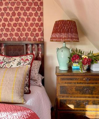 pink bedroom with a dark wooden bedroom and a large pink and red tapestry hung behind the bed decorated with vintage antique decor and furniture