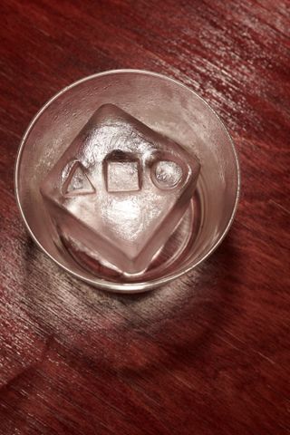 glass with ice cube with symbols carved on top