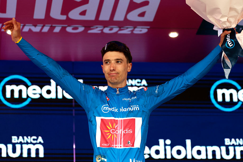 Cofidis' Belgian rider Sylvain Moniquet wears the best climber's blue jersey on the podium after the first stage of the 108th Giro d'Italia cycling race, 160km from Durres to Tirana in Albania, on May 9, 2025. (Photo by Luca Bettini / AFP)